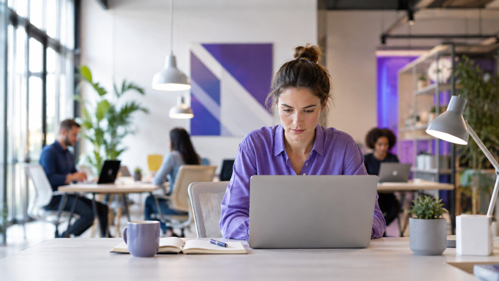 Frau arbeitet konzentriert an einem Laptop in einem modernen Coworking Space